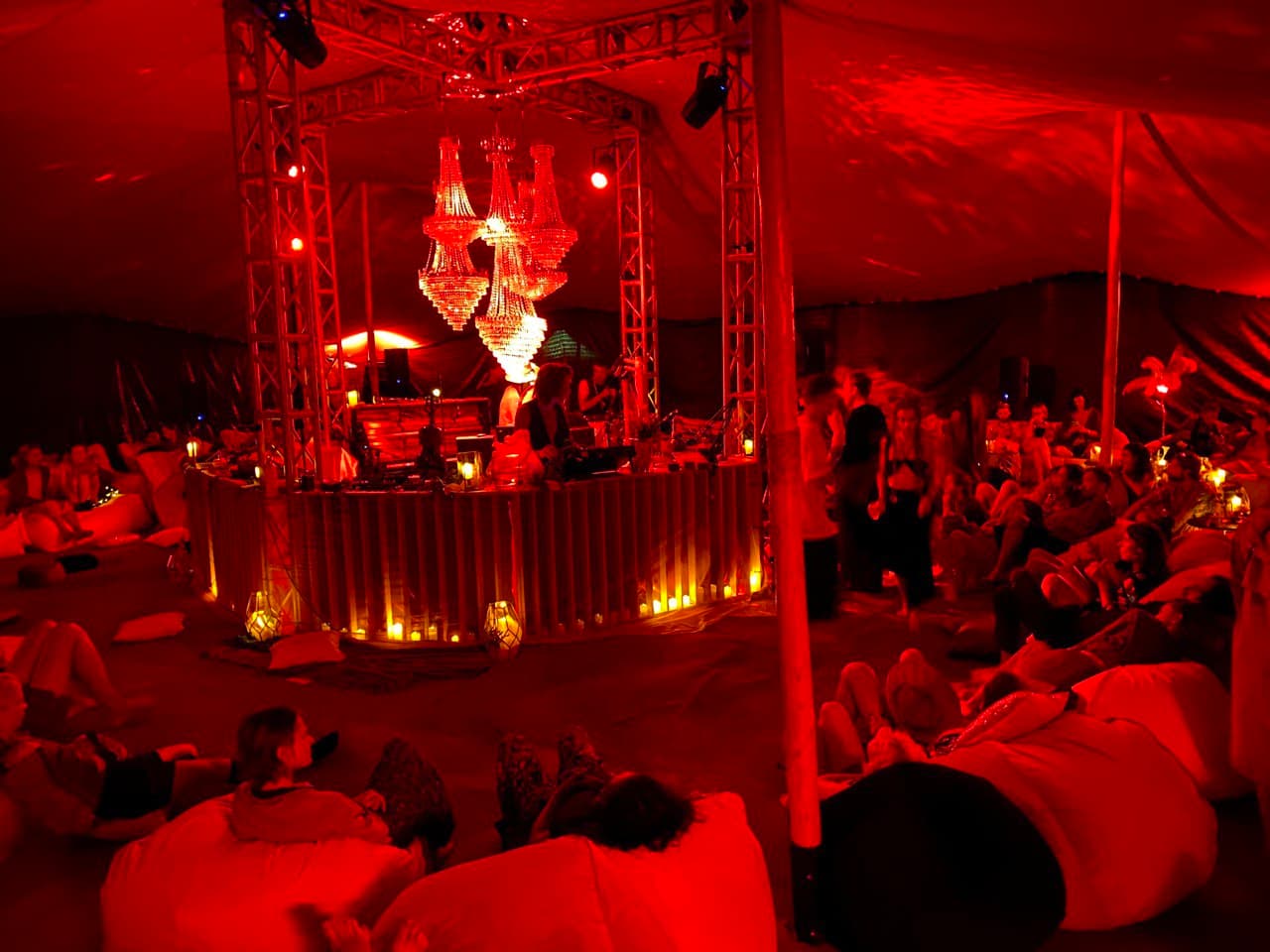 Jam Hall in saturated red light — the chandelier installation above the booth and the audience gathered around it