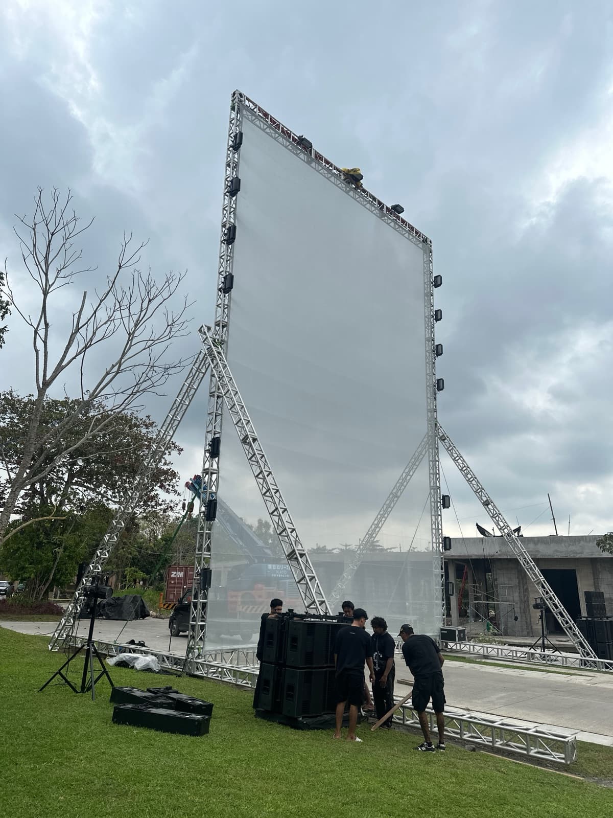 The finished rig — translucent screen suspended on truss, daytime, audience-area cleared, ready for nightfall.
