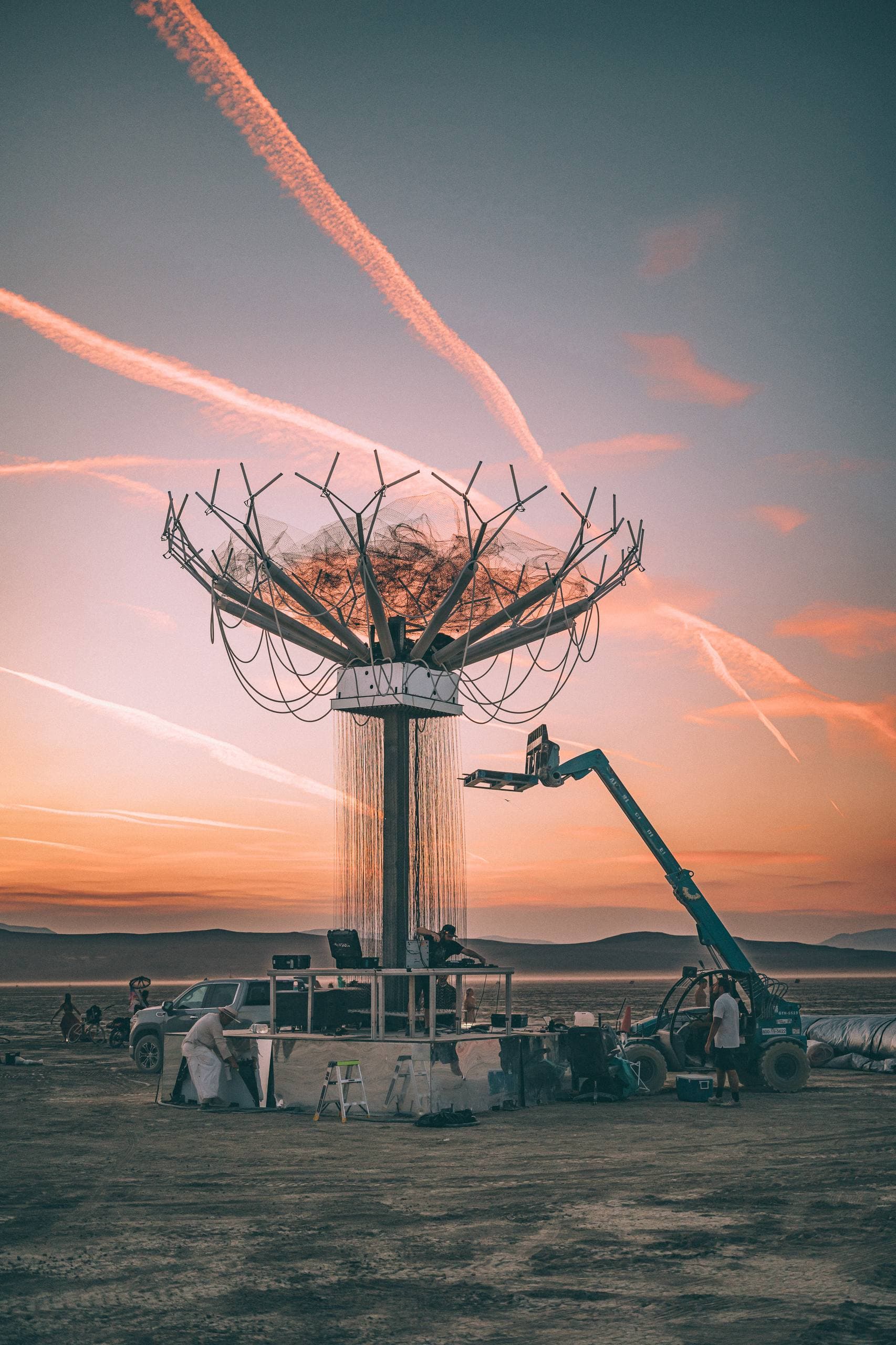 Singularity Tree under construction on the Playa at sunset, with crew and lifting equipment at its base