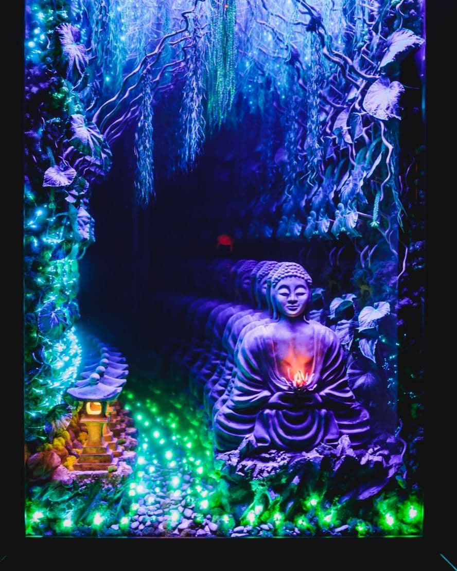 An infinity mirror opens onto a glowing willow and a meditating Buddha at its centre.