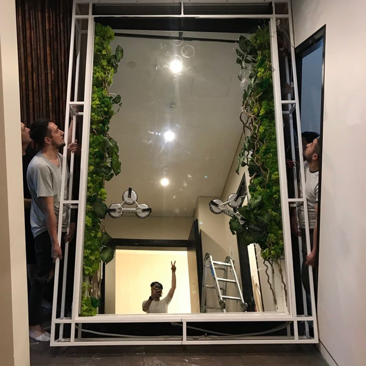 Mounting the infinity-mirror frame — the studio team installing the steel cage in the apartment hallway.