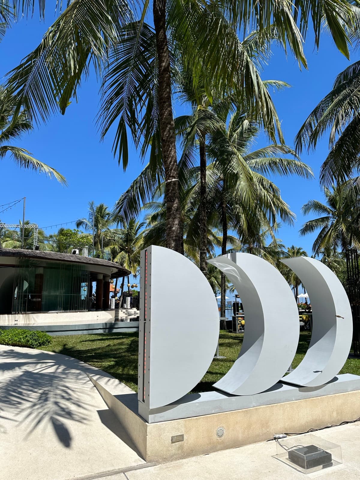 Detail — three crescents seen from below, blue sky and palms above.